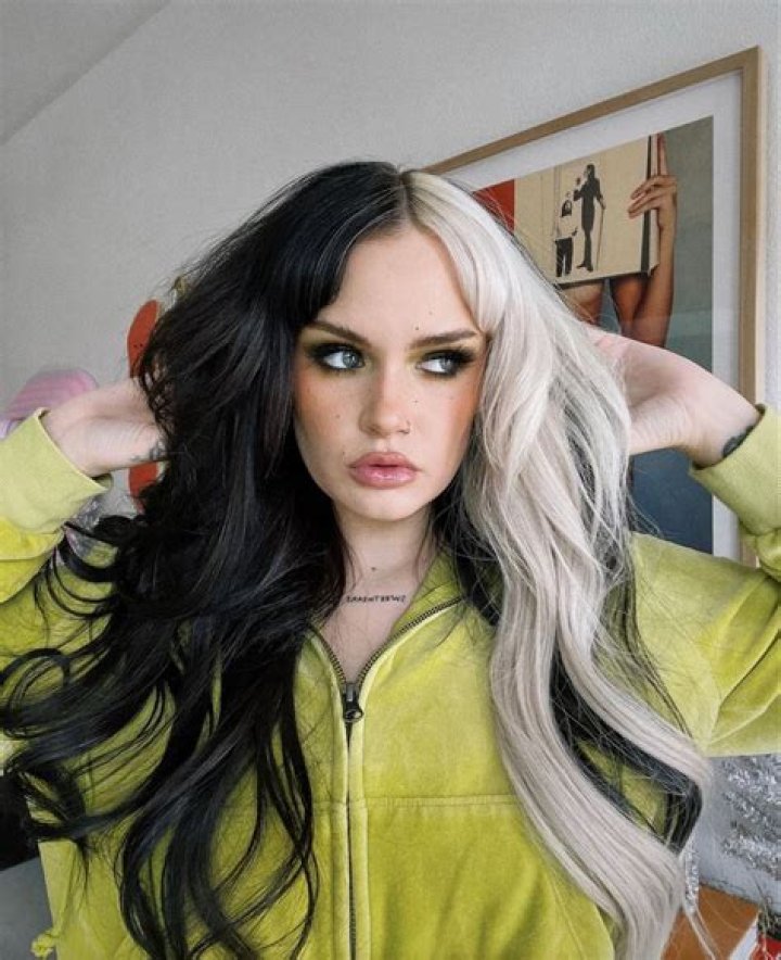 Ash Levi split hair colors (blonde and brunette) posing.
