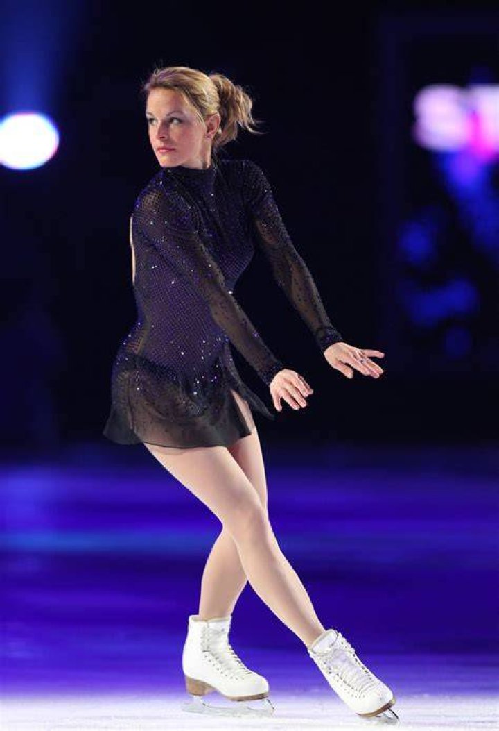 Ekaterina Gordeeva in a light blue t-shirt and black pants showing her tattoo.